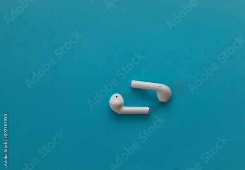Small wireless headphones in white - on a blue background photo