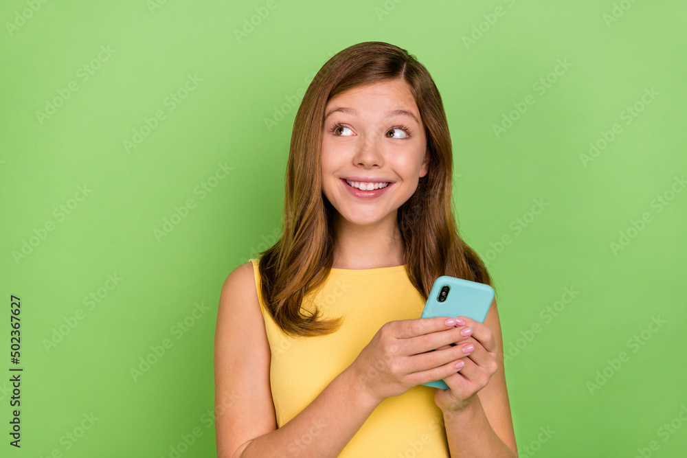 Photo of young lovely lady curious look empty space use mobile phone repost share isolated over green color background Photo of young lovely lady curious look empty space use mobile phone repost share isolated over green color background