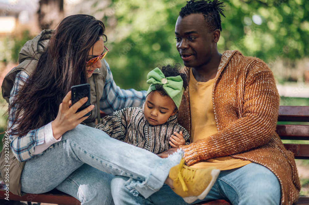 Multiracial family of three taking selfie with a smartphone in the park Multiracial family of three taking selfie with a smartphone in the park