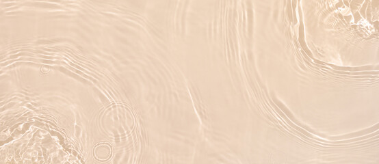 Abstract summer banner background Transparent beige clear water surface texture with ripples and splashes. Water waves in sunlight, copy space, top view. Cosmetics moisturizer micellar toner emulsion