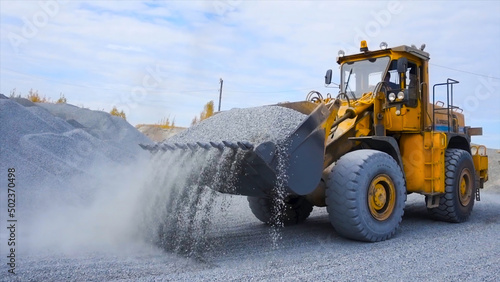 Tractor on construction site carries rubble. Stock footage. Tractor work on construction site or mining. Yellow tractor raking rubble from pile