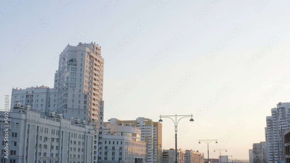 Road lights on background of white city buildings. Stock footage. Beautiful highway lights on background of white multi-storey buildings at dusk. Urban architecture with road lights and white