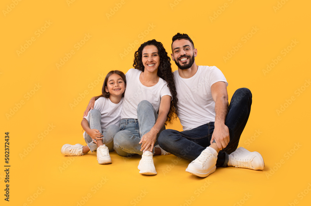 Middle Eastern Parents And Daughter Embracing Sitting On Yellow Background Middle Eastern Parents And Daughter Embracing Sitting On Yellow Background