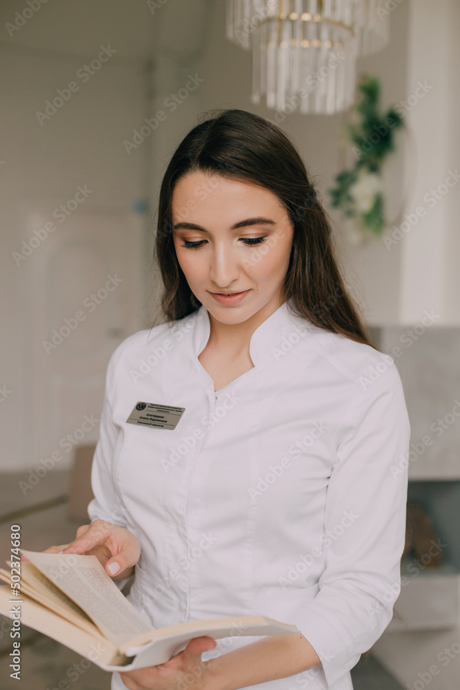 woman doctor in a white coat standing with a book in her hands in the clinic woman doctor in a white coat standing with a book in her hands in the clinic