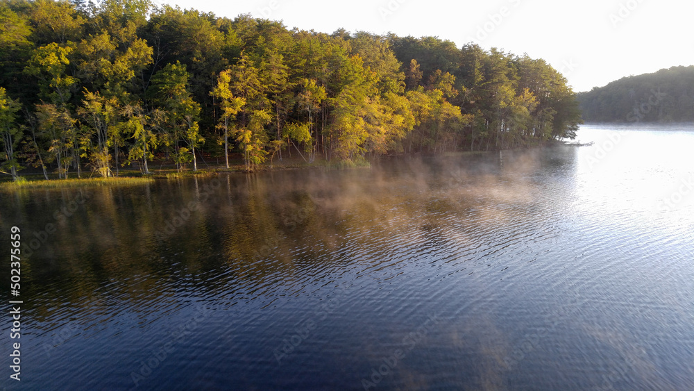 Landscape with trees reflected in a morning lake Landscape with trees reflected in a morning lake