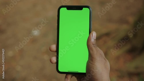 Close-up of the hand of a black man with a mobile phone with a green screen