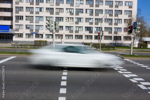 Blurred white car movement along the avenue at daytime. © leon134865
