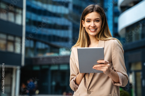 Portrait of a successful business woman using digital tablet in front of modern business building photo