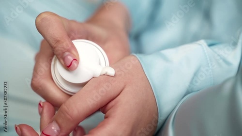 a girl squeezes a cream from a tube onto her hand in blue pajamas close-up