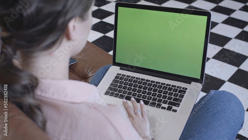 New technology concept. Stock footage. Young woman in pink at home typing on the keyboard and looking at the laptop screen with chroma key green screen.