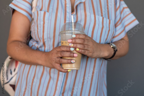 Close up shot of woman with pastel colored nails with drink