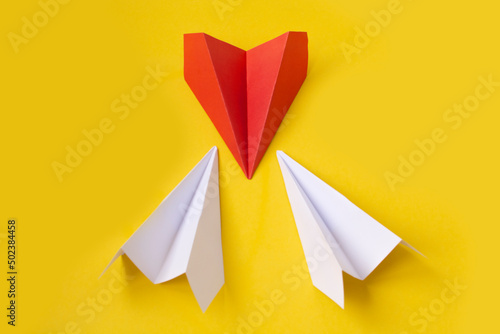 Red paper plane changing direction from white paper plane on yellow background. business concept for new ideas creativity