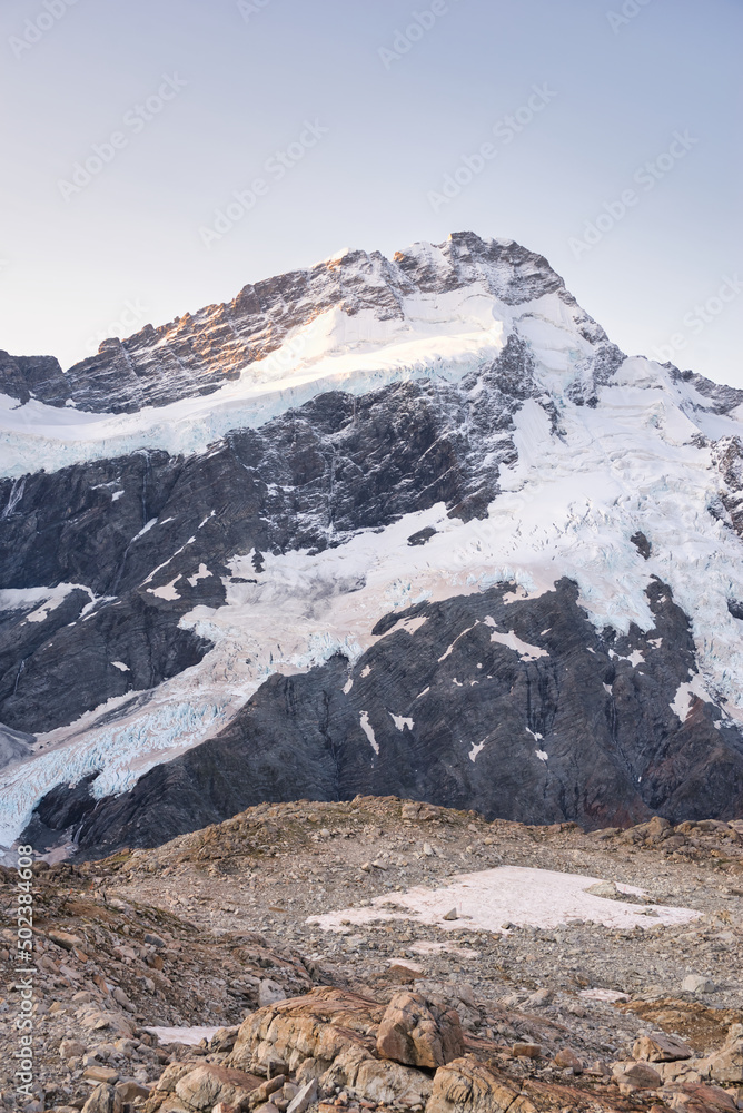 Pastel colored view on a perfect mountain that is covered in snow and glacier fields with some gravel in the foreground making it a perfect background for a outdoor/ adventure advertisement. 
