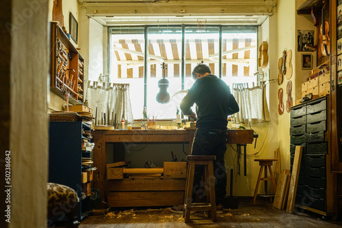 Back view of a violin maker working in a workshop photo