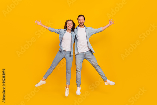 Full length body size view of attractive cheery funny people jumping having fun isolated over bright yellow color background