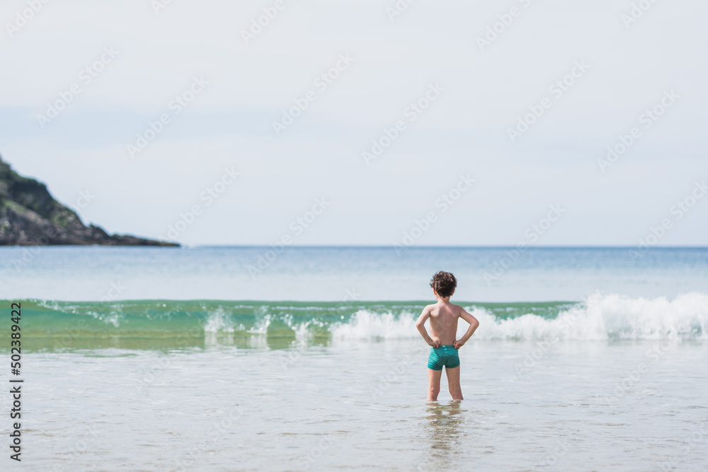 Unrecognizable boy standing towards sea Unrecognizable boy standing towards sea