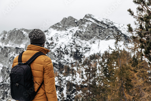 Back view of a Caucasian man with backpack and winter clothes hiking in the Julian Alps in Slovenia photo