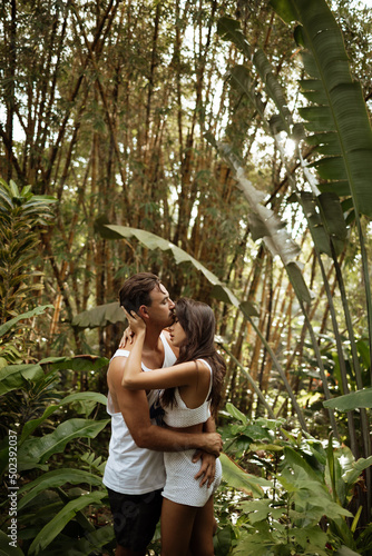 Beautiful happy couple hugging near the pool against the backdrop of palm trees © Yevhenii