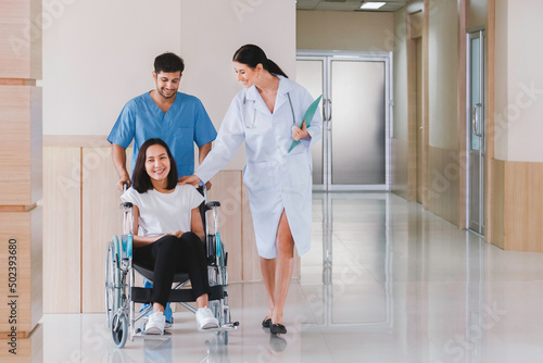 happy smiling asian patient woman sitting in wheelchair with male nurse talking to doctor after recovering from surgery treatment plan in the hospital. healthcare and medical concept