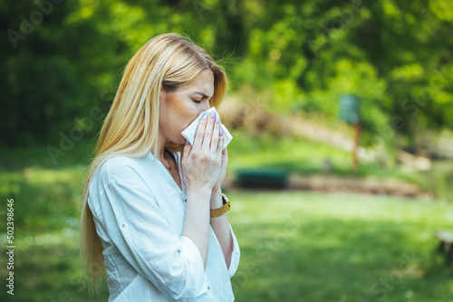 Woman with allergy symptom blowing nose. Attractive Woman Outdoors is Having Allergy. Woman Blowing Her Nose With Handkerchief In Public Parkf. Sick Young Woman With Seasonal Influenza