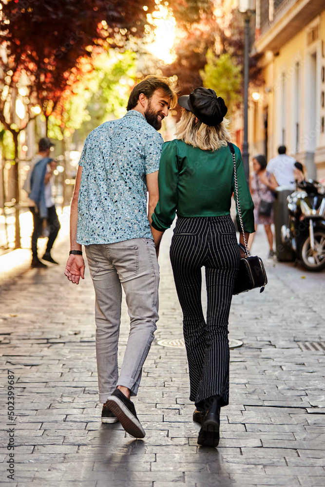 Couple walking on street away from camera.