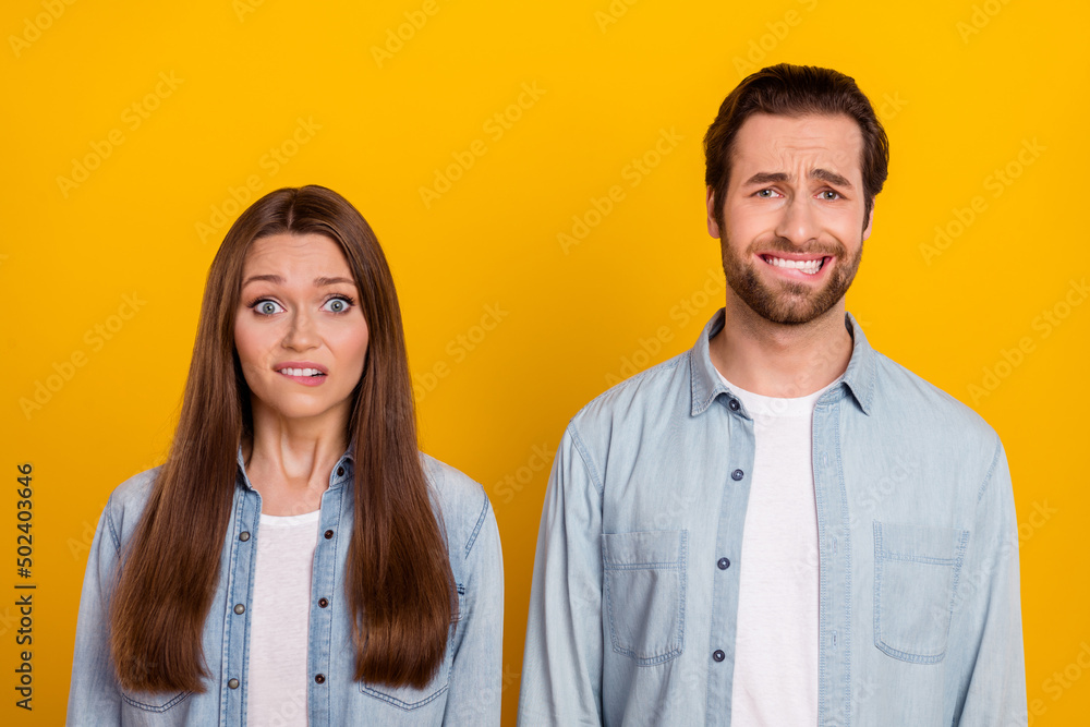 Photo of doubtful unsure husband wife wear jeans shirts biting lips knowing bad news isolated yellow color background Photo of doubtful unsure husband wife wear jeans shirts biting lips knowing bad news isolated yellow color background