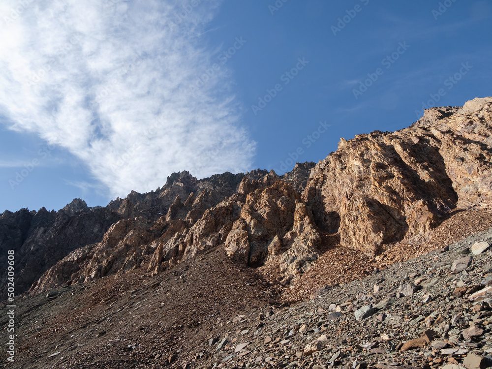 Rockfall and stone meadow, minerals scattered on the field. Minimalist landscape with mossy red stones in sunlight in mountains. Summer minimalism in mountains.