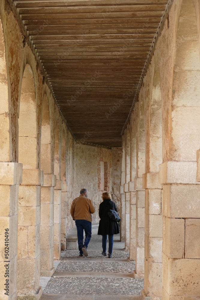 Una pareja de adultos camina bajo los arcos de una iglesia.