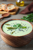 Bowl of delicious asparagus soup on wooden table, closeup