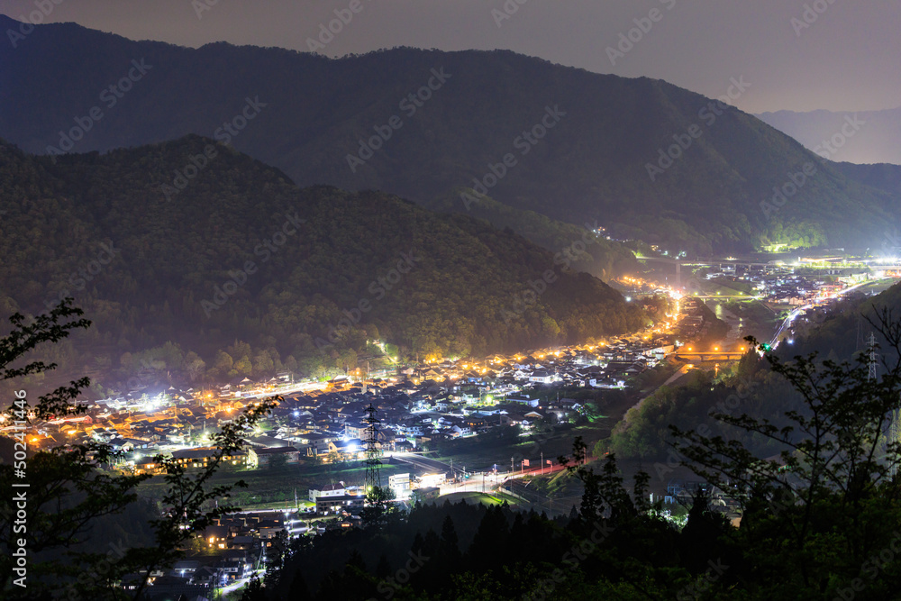 Small village lit up between dark mountains at night