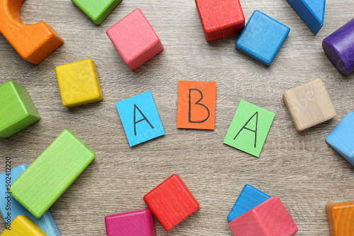 Canvas-taulu Colorful building blocks and cards with abbreviation ABA on wooden table, flat l