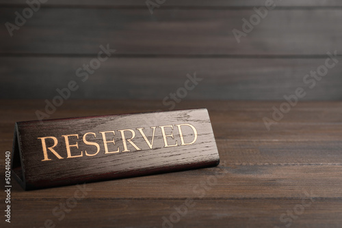 Elegant sign RESERVED on wooden surface, space for text. Table setting element