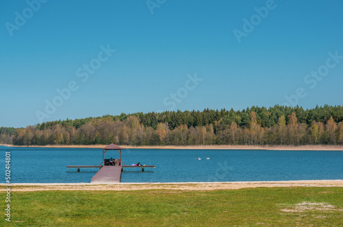 People resting on a pier over the tranquil Deczno lake in Swiecie, Poland photo