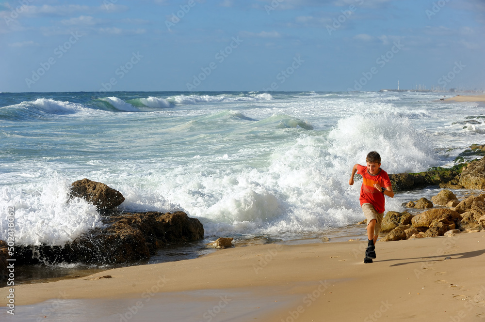 Boy runs along the shore of the Mediterranean Sea in Israel Boy runs along the shore of the Mediterranean Sea in Israel