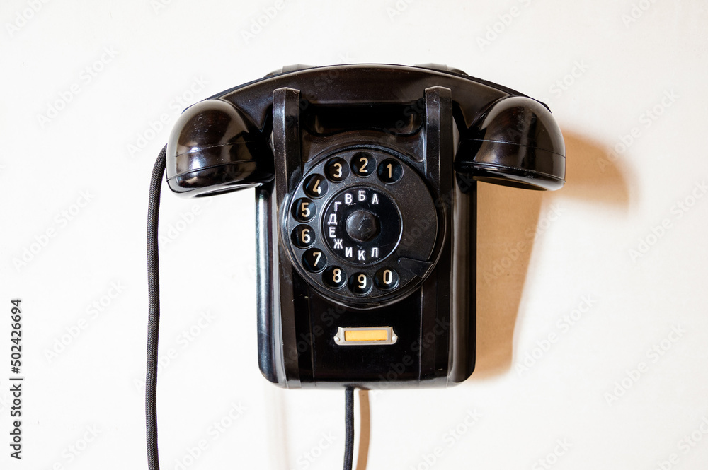 The old phone with a dial dial is wall mounted.
