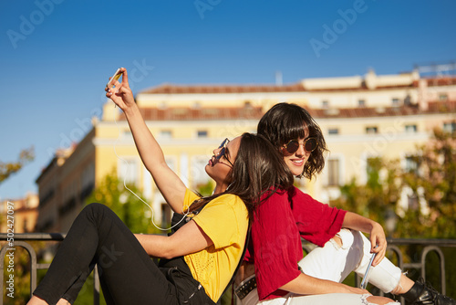 Two teenager girls sitting and taking selfie.