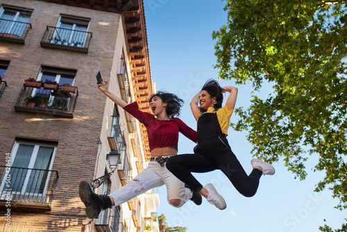 Two teenager girls jumping and taking selfie.