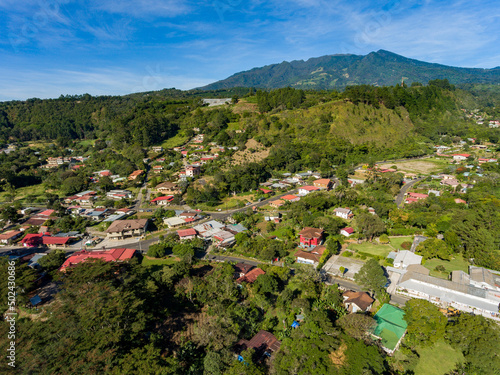 Aerial shot of a village surrounded by greenery on hilly terrain in the countryside photo