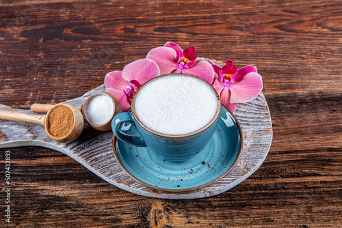 Close up white cup of salep milky hot drink on wooden background. Cup of salep milky traditional hot drink of Turkey with cinnamon served in a porcelain cup. photo