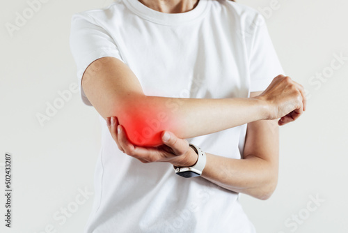 Arm pain and injury for woman. Closeup side body with painful elbow isolated on beige background photo
