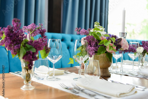 Φωτογραφία Selective focus shot of lilac flowers in vases and other settings on a wooden ta