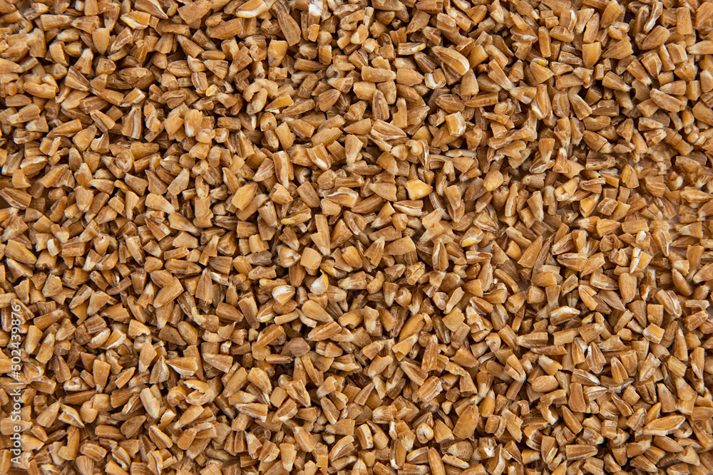 Handful of crushed whole wheat grain background,top view.