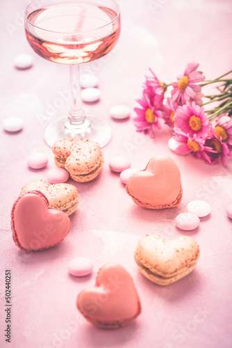 Happy Mothers Day - sweet macarons and glass of rose sparkling wine with flowers in pink tone