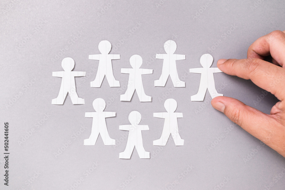 Closeup man arrange the paper human on board to explain about group of people, social and crowd, building a team, or collaboration concept Closeup man arrange the paper human on board to explain about group of people, social and crowd, building a team, or collaboration concept