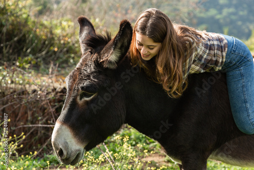 Foto A happy young woman riding a donkey in the meadow