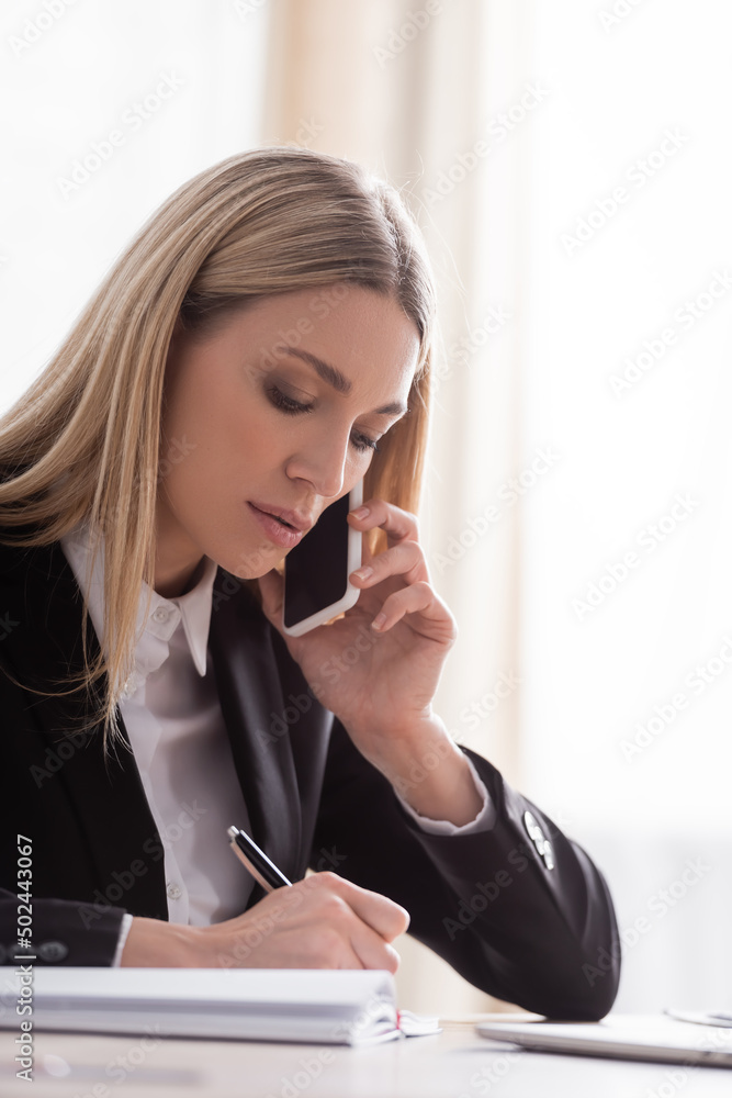 blonde notary talking on mobile phone and writing in office. blonde notary talking on mobile phone and writing in office.