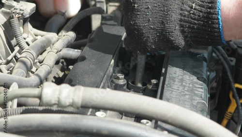 a man unscrews the spark plugs on the car engine. Work under the hood of the car. scheduled maintenance