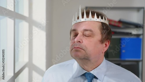 Portrait of smug man puts crown on his head with pride, megalomania. photo