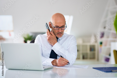 Executive businessman using mobile phone and laptop while working at the office