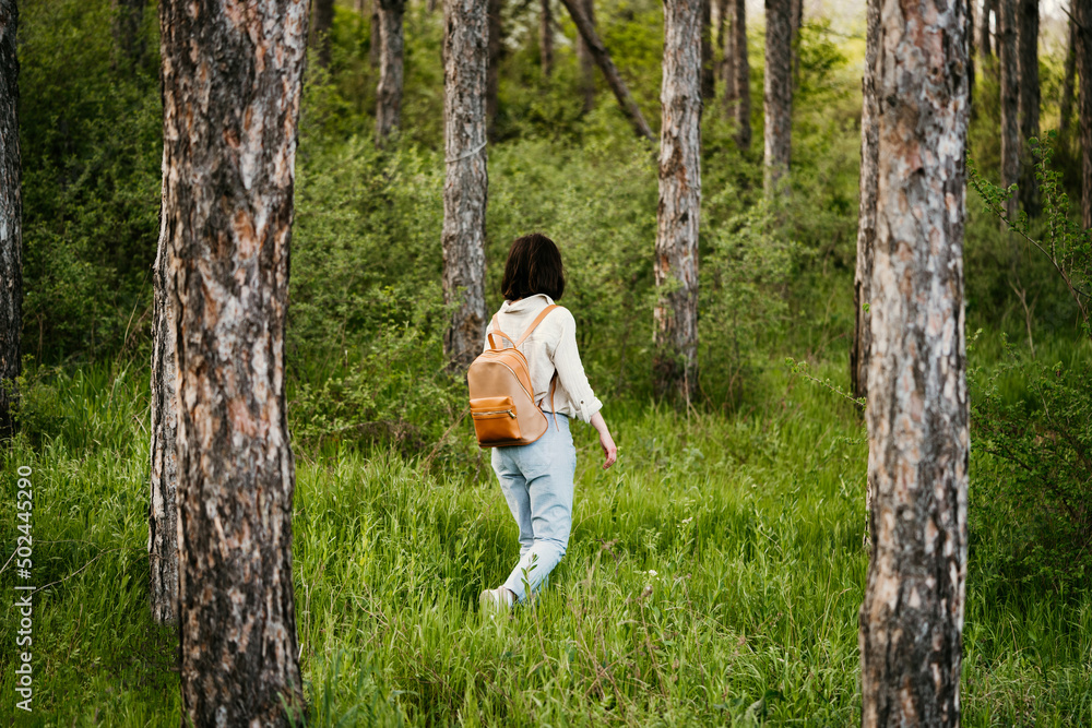 Young woman with backpack walking alone in a forrest Young woman with backpack walking alone in a forrest